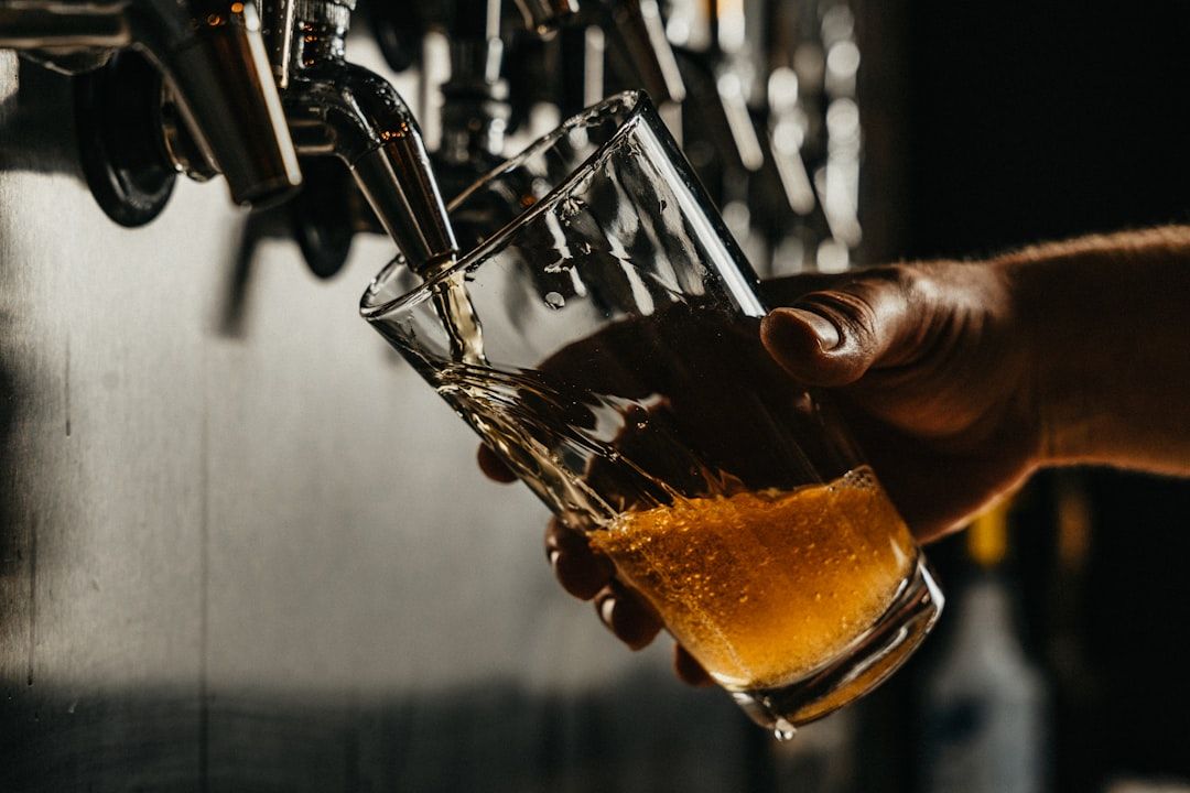 A person pours a fresh, golden beer from a metallic tap into a tilted glass.